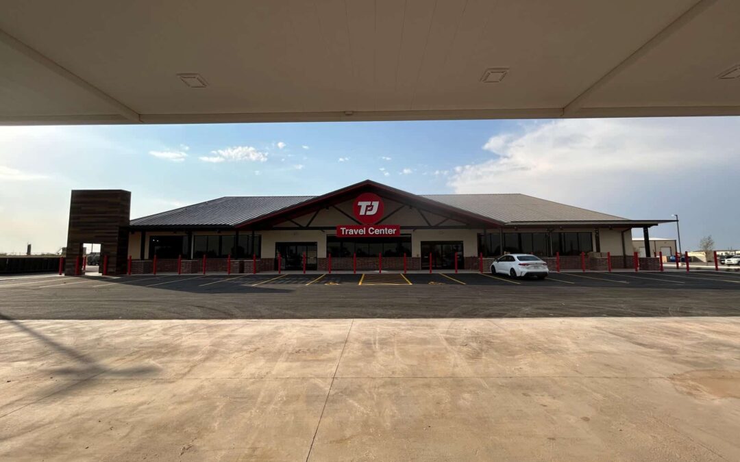 Freshly paved asphalt parking lot in front of a TJ Travel Center, showcasing clean lines and smooth surfaces.