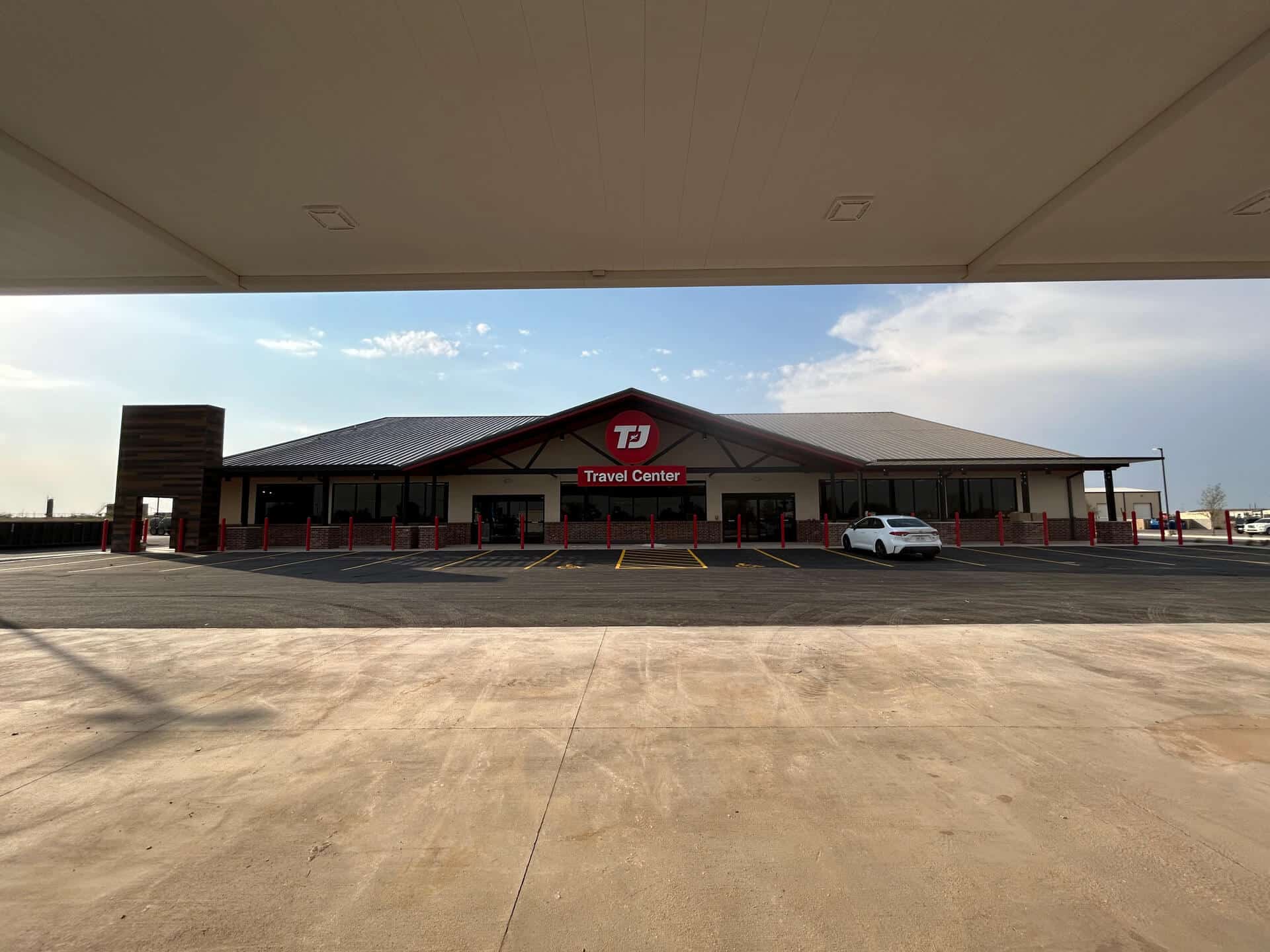 Freshly paved asphalt parking lot in front of a TJ Travel Center, showcasing clean lines and smooth surfaces.