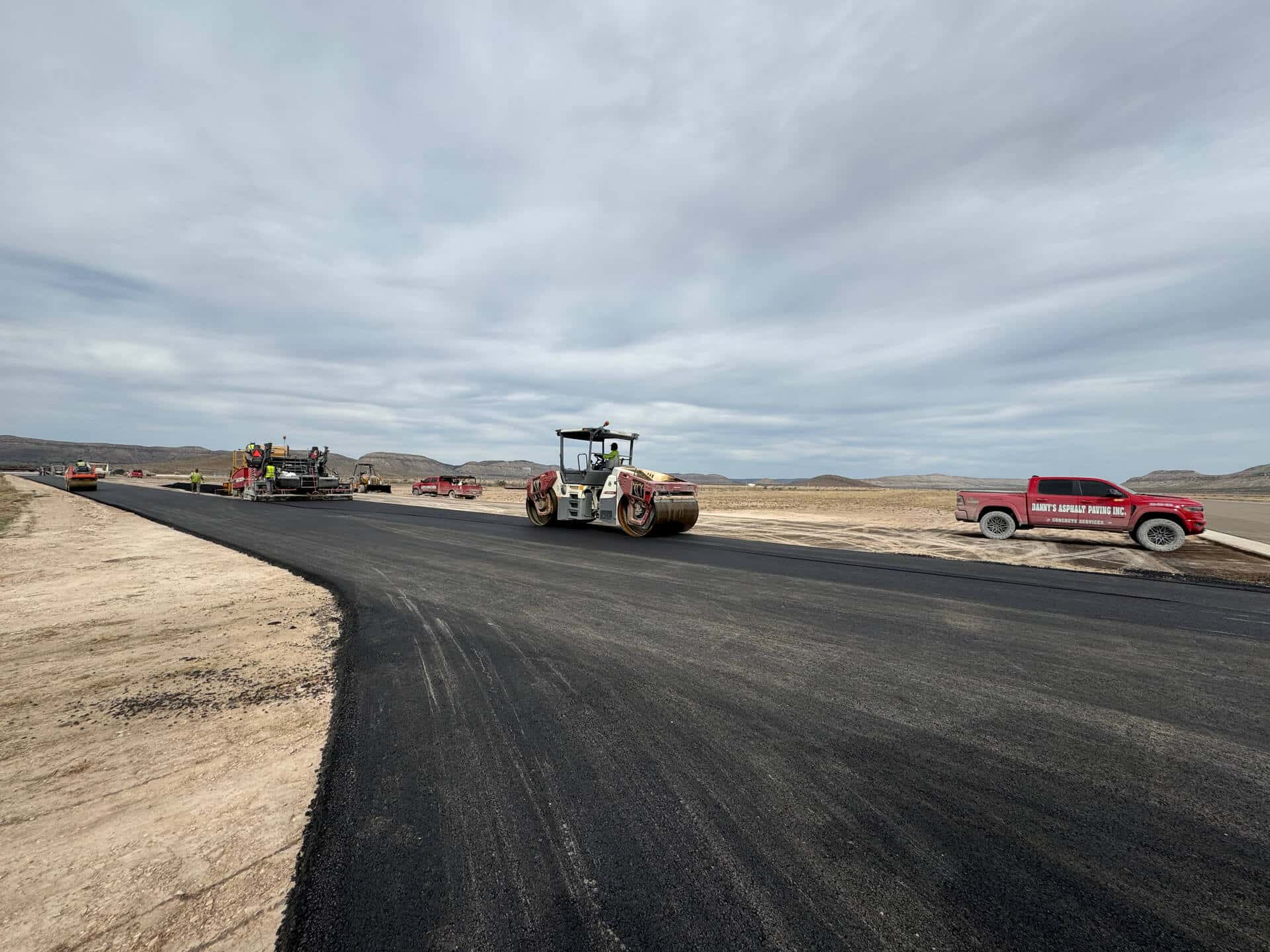 Construction crew and equipment paving a road in Texas, showcasing Danny's Asphalt Paving's quality and expertise.